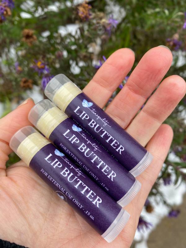 Three lip butters in the palm of a hand.